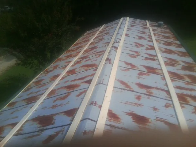 Rusted metal roof panels with new wood purlins before replacement — Storm Damage Roof Repair in North Henderson by Roofing Brothers