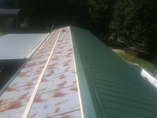 Old rusted panels beside newly installed green metal roofing — Wind Damage Roof Repair by Roofing Brothers in North Henderson