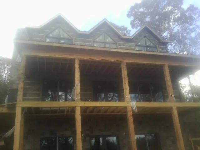 Dormers and porch framing on a large log home under construction — Roof Coating work by our crew in North Henderson