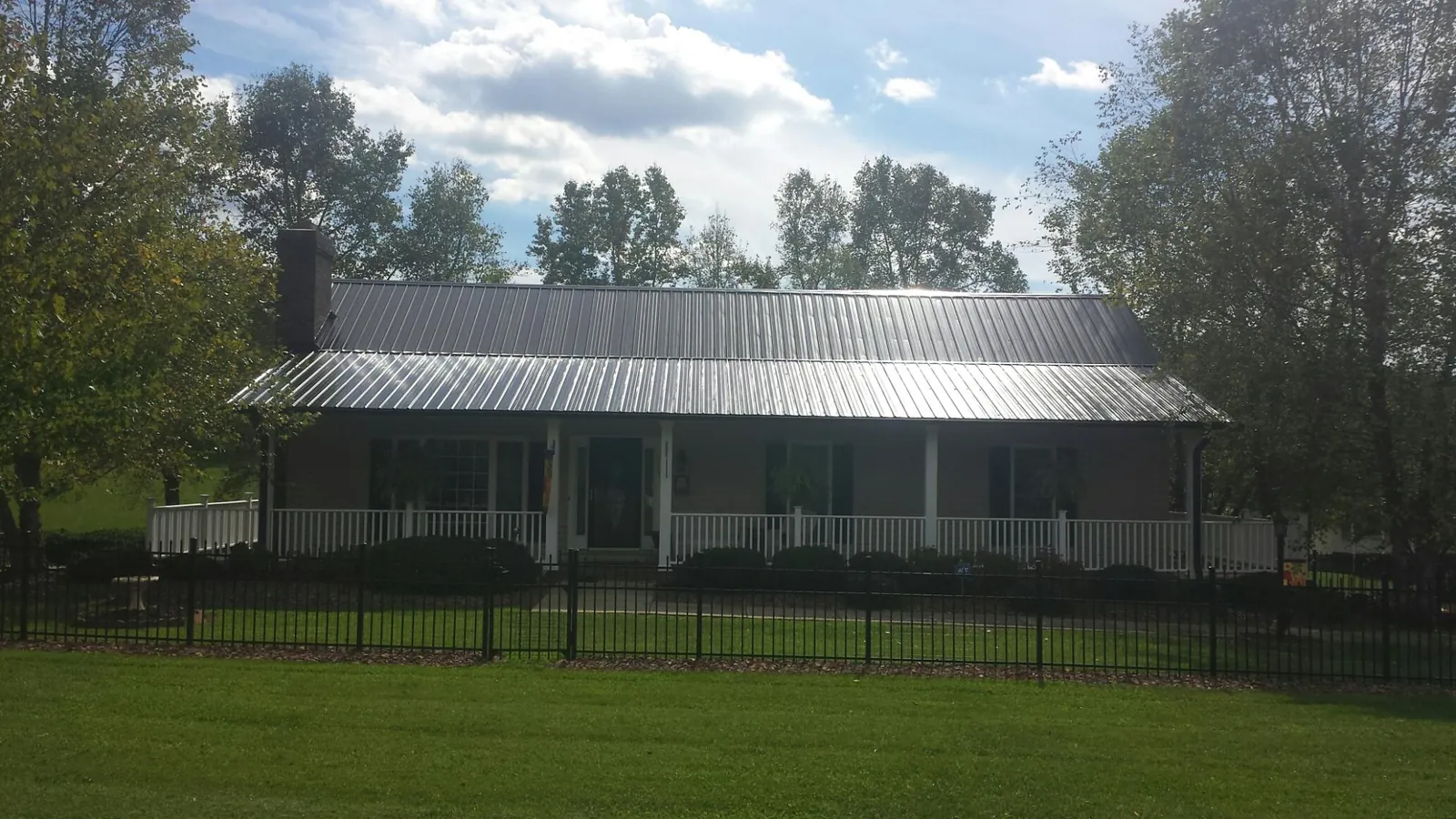 Gray metal roof on a brick ranch with a full width front porch — Gutter Guard Installation work by our crew in North Henderson