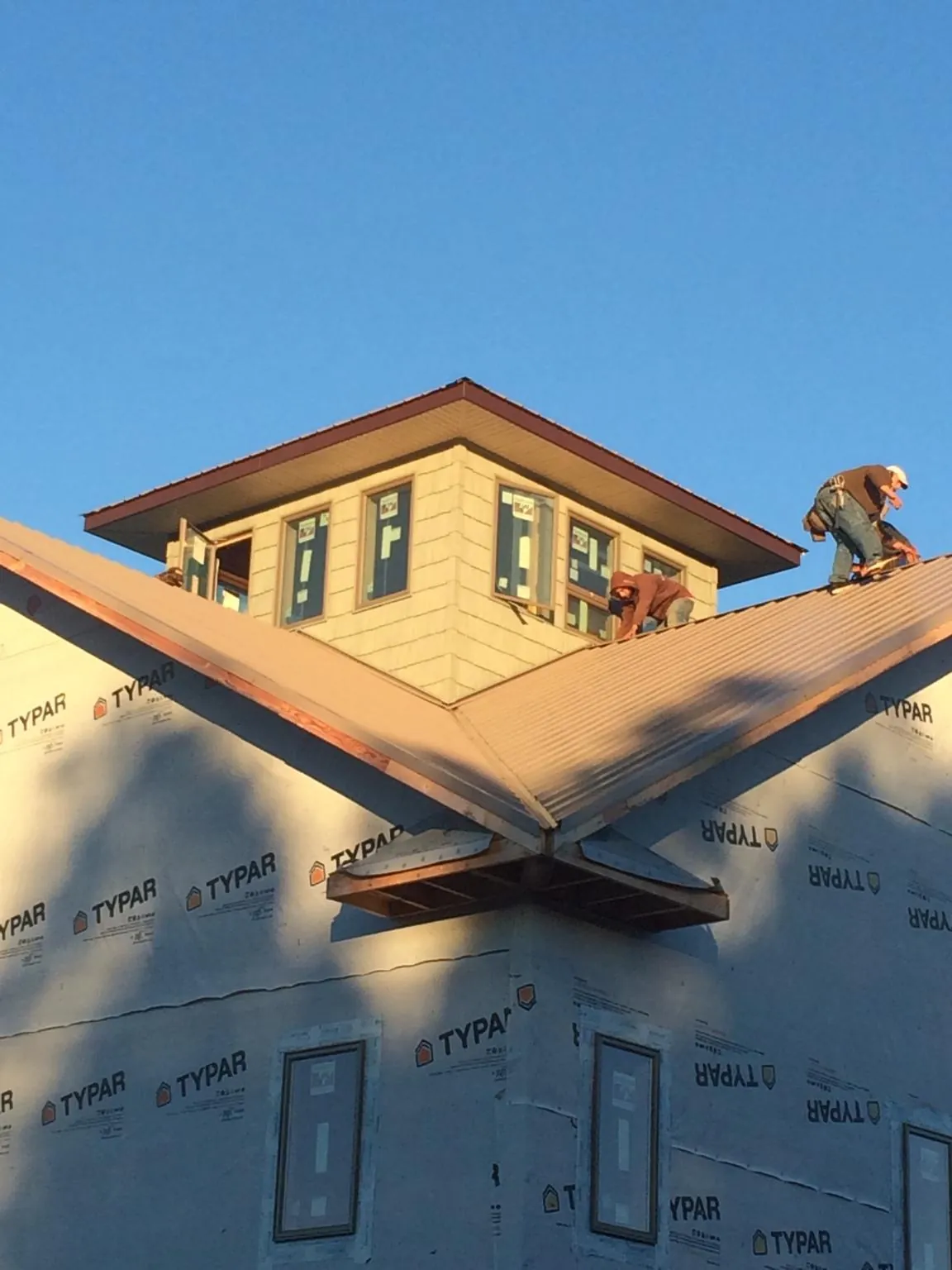 Roofers working around a rooftop cupola on a new metal roof at sunset — Roof Waterproofing in North Henderson by Roofing Brothers